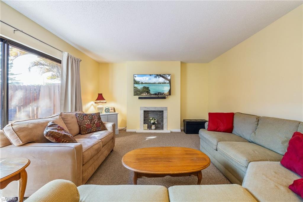 Carpeted living area featuring a fireplace with raised hearth and a textured ceiling