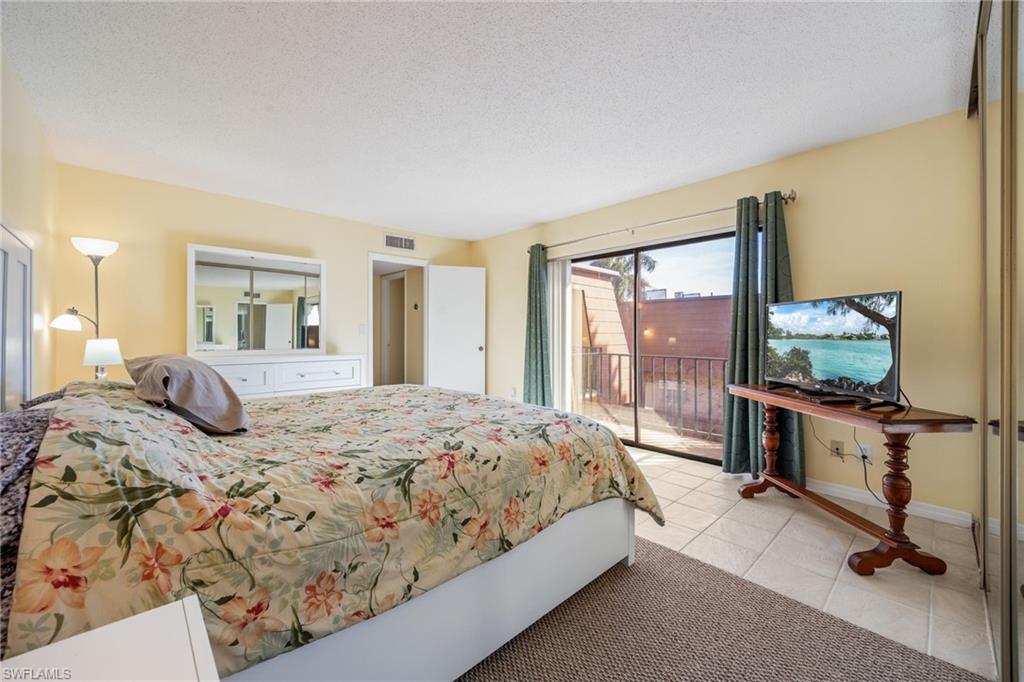 Bedroom featuring access to outside, a textured ceiling, light tile patterned floors, and light colored carpet