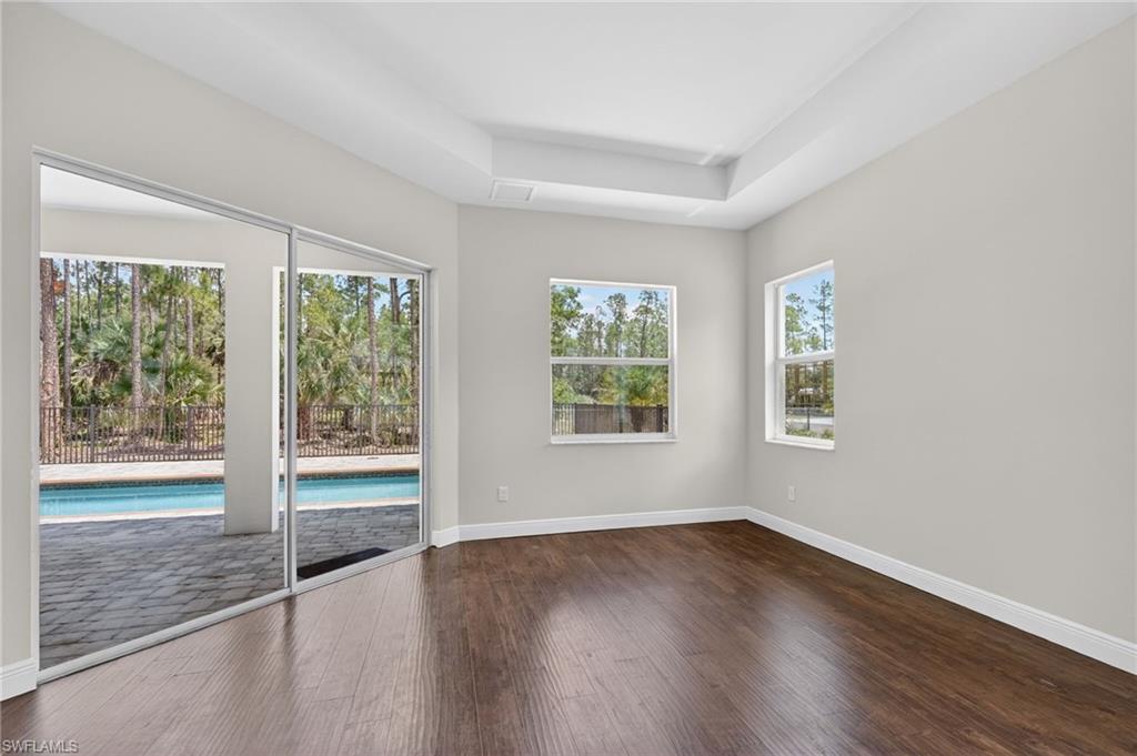 Primary bedroom with tray ceiling and sliders to outdoor area and Pool