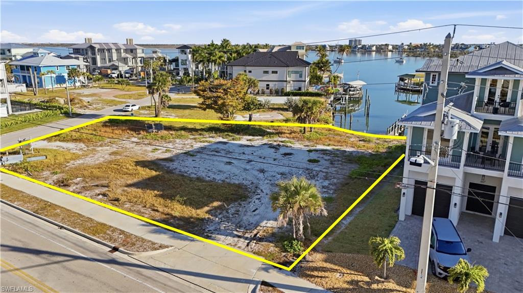 Aerial view of residential area featuring a nearby body of water and property parcel outlined - Virtually Edited Image