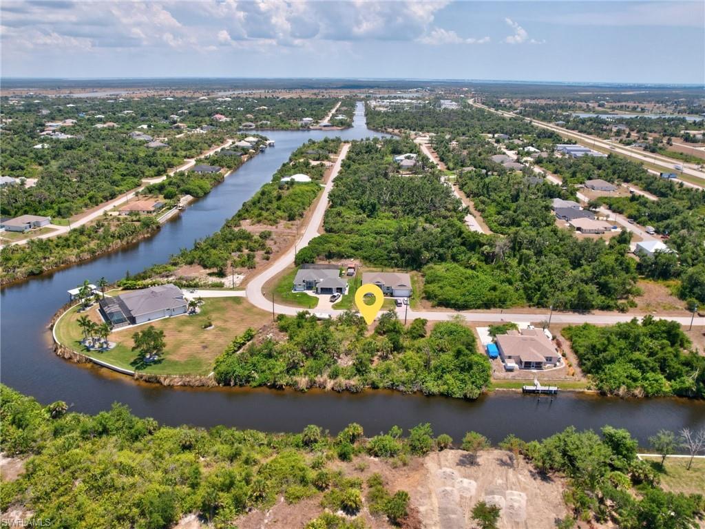 Aerial view of property's location with a tree filled landscape and a nearby body of water