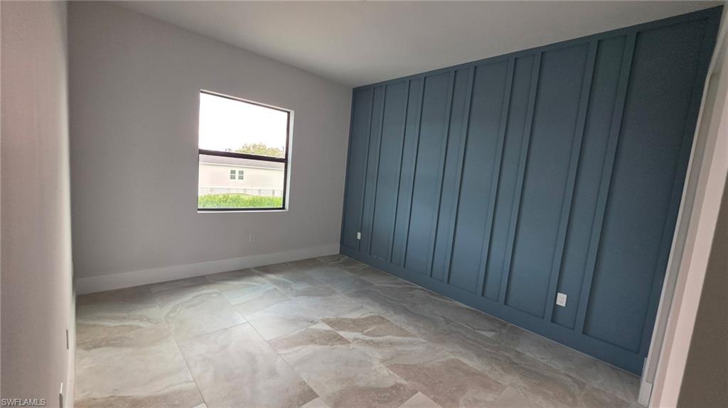 Accent wall with vertical paneling, vaulted ceiling, large window, and tile flooring