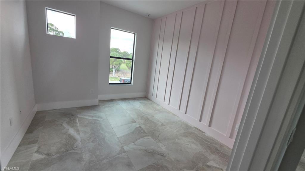 Vaulted ceiling with recessed lighting, large format tile flooring, and an accent wall featuring vertical paneling