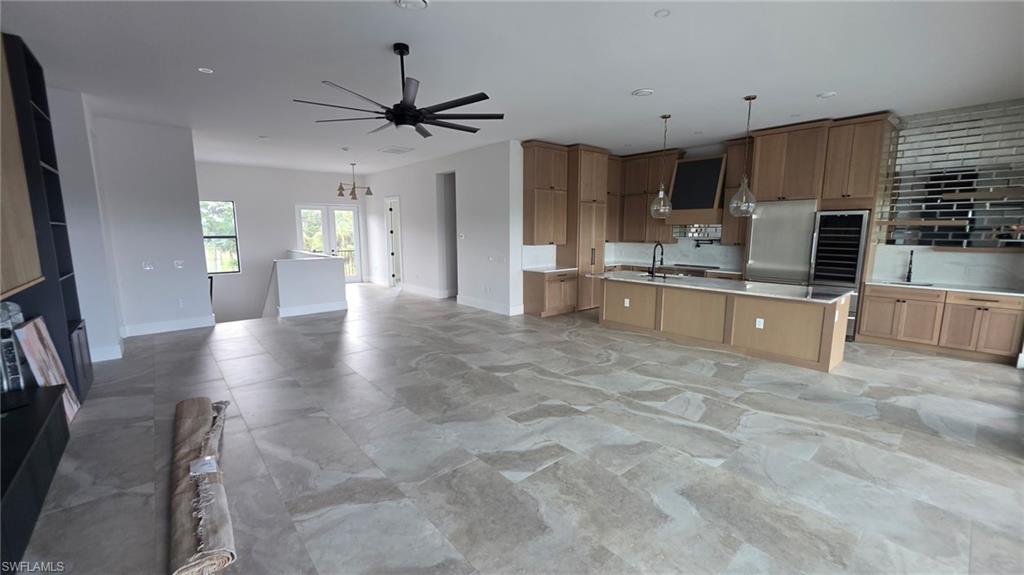 Gourmet kitchen with light wood-finish cabinetry, stainless steel appliances, and a central island with countertop seating