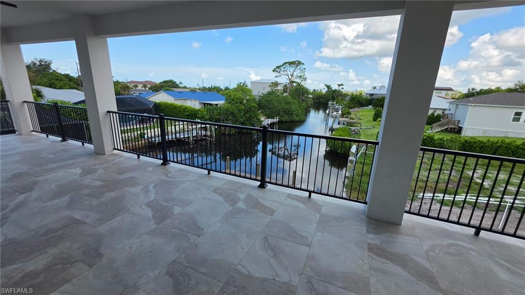 Expansive outdoor balcony with large format tile flooring, black metal railings, and waterfront canal scenery