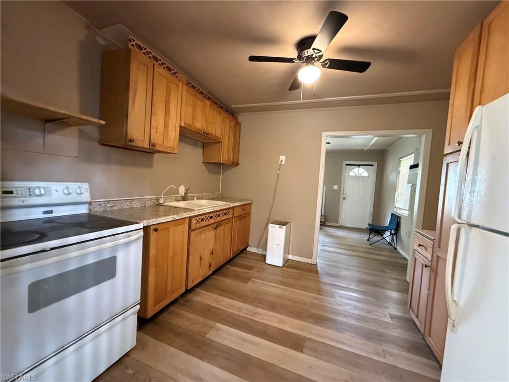 Kitchen featuring white appliances, a ceiling fan, light wood finished floors, light countertops, and wood finish cabinets