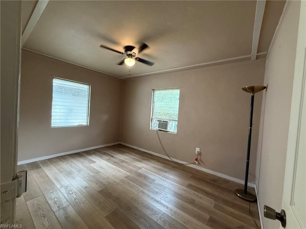Empty room with light wood finished floors, a ceiling fan, and cooling unit