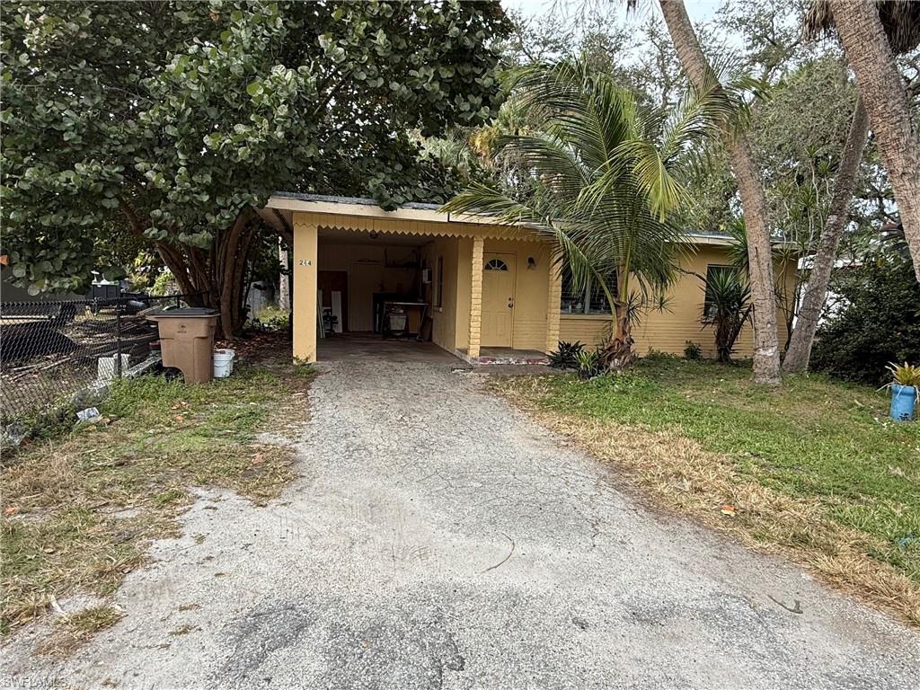 View of front of home featuring driveway, stucco siding, and a carport