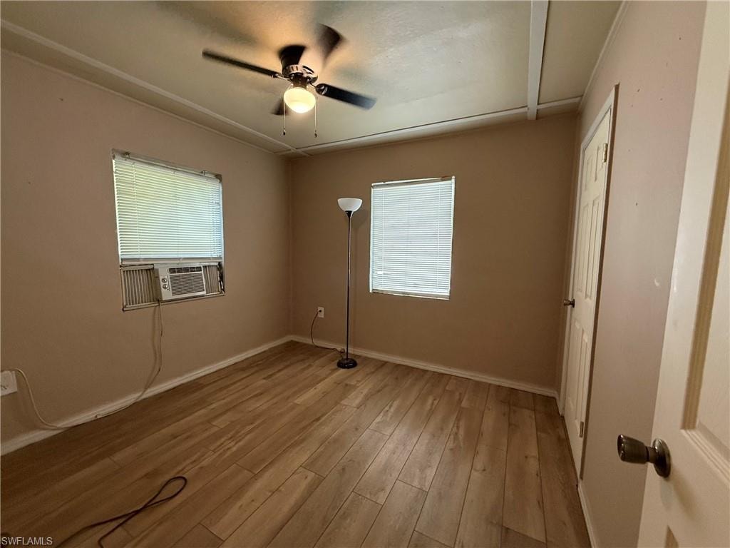 Unfurnished bedroom featuring a ceiling fan, light wood-style flooring, a closet, and cooling unit