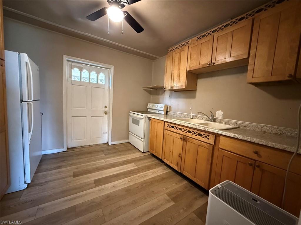 Kitchen with ceiling fan, white appliances, light countertops, wood finish cabinets, and light wood-style floors