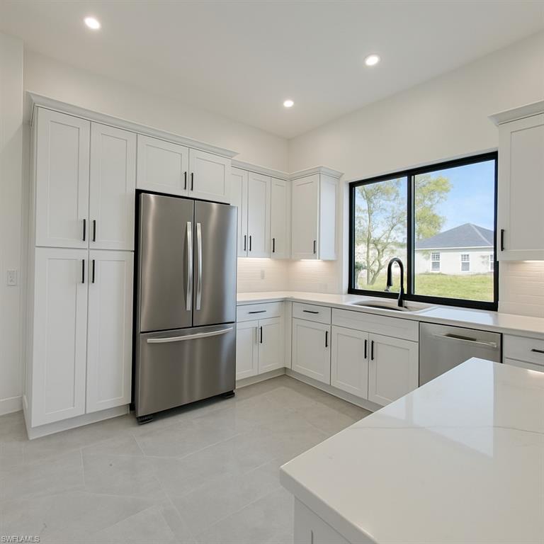 Kitchen with stainless steel appliances, white cabinets, tasteful backsplash, light stone counters, and recessed lighting