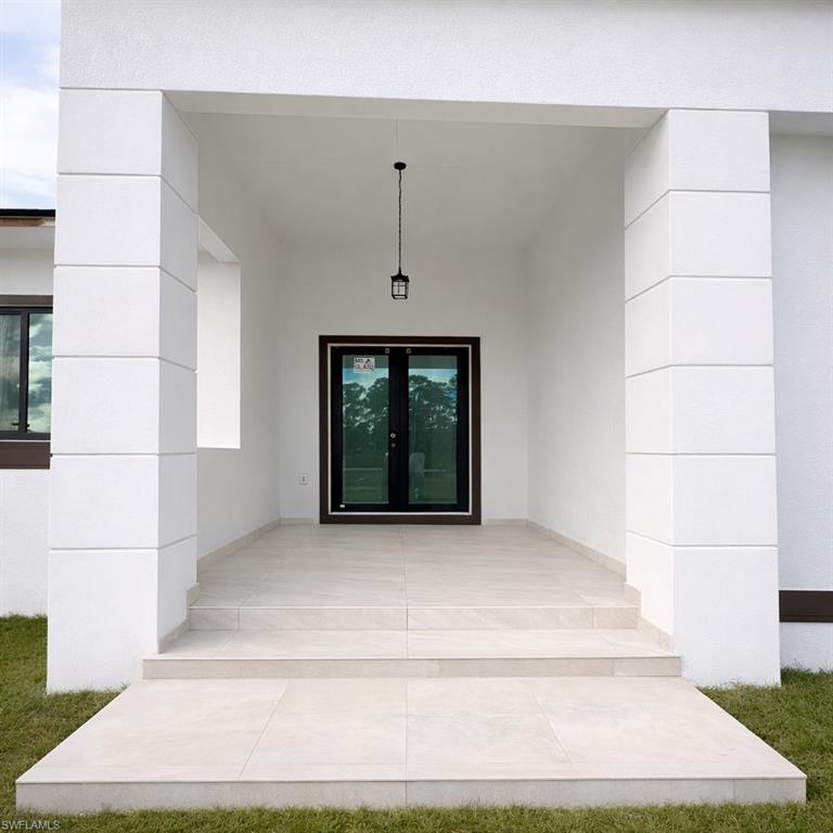 Entrance to property with french doors, stucco siding, and a patio