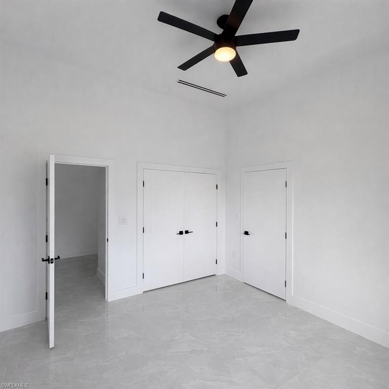 Unfurnished bedroom featuring a closet, a ceiling fan, and a high ceiling