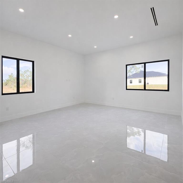 Unfurnished room with healthy amount of natural light and recessed lighting