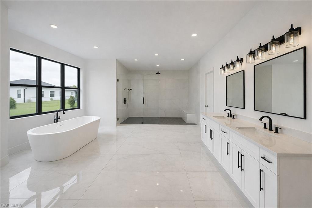 Bathroom featuring a shower stall, a freestanding bath, double vanity, and recessed lighting