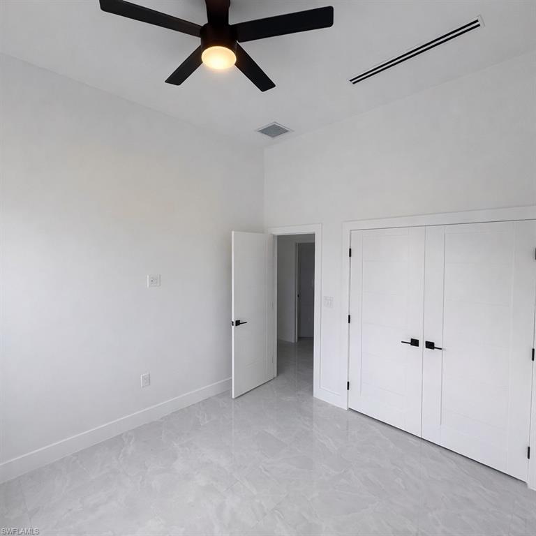 Unfurnished bedroom featuring ceiling fan, a closet, and a high ceiling