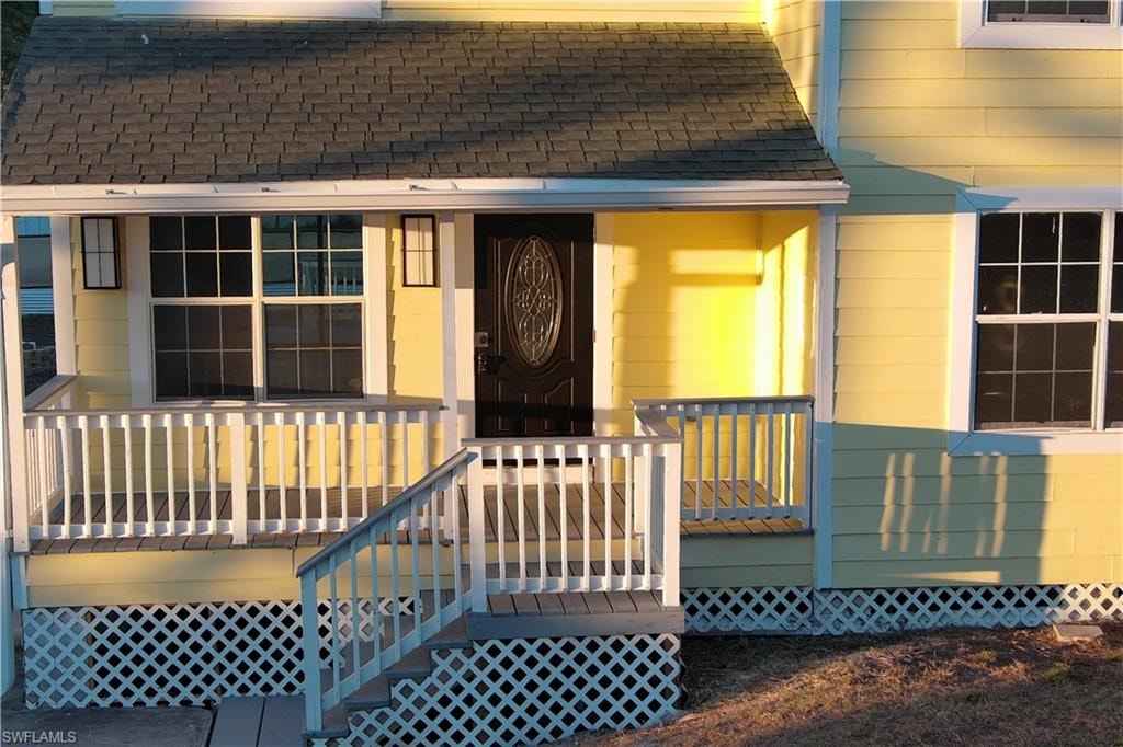 Entrance to property with roof with shingles and a deck