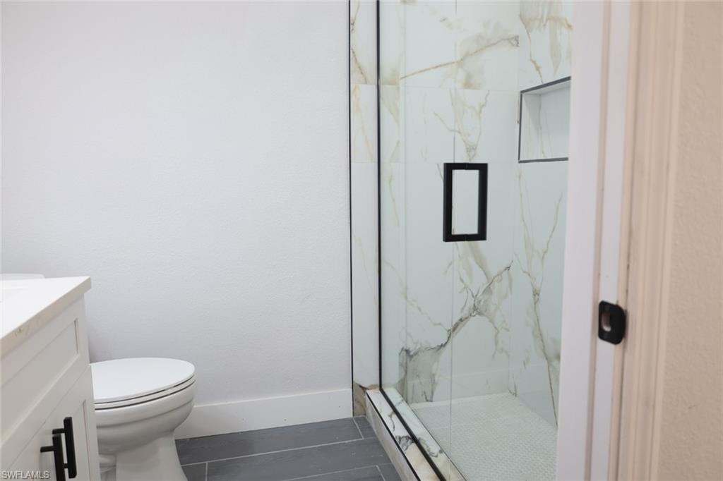 Full bath featuring a marble finish shower and vanity