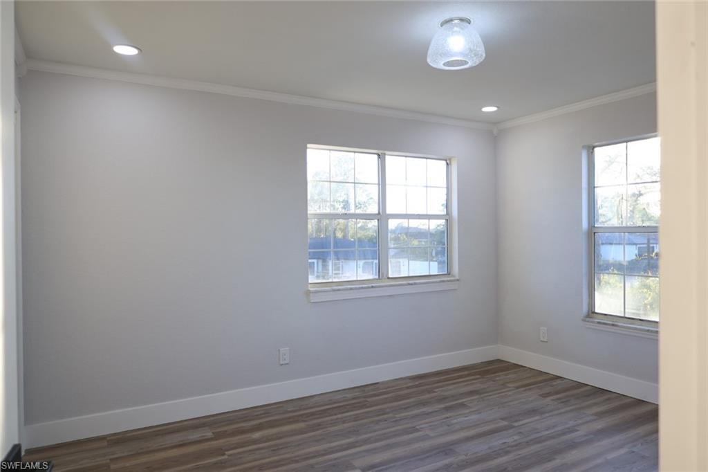 Unfurnished room featuring dark wood-style flooring, crown molding, and recessed lighting