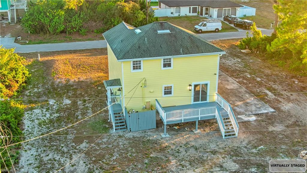 Rear view of property with stairs, a shingled roof, and a deck