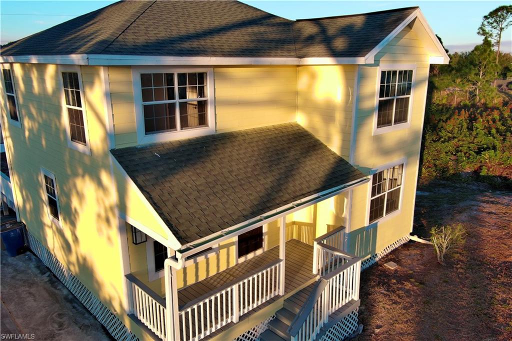 Back of house with a shingled roof and covered porch