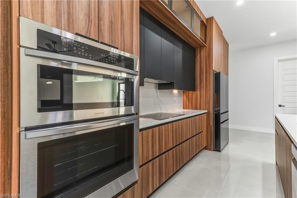 Kitchen featuring stainless steel appliances, modern cabinets, glass insert cabinets, two tone color scheme, and light quartz counters