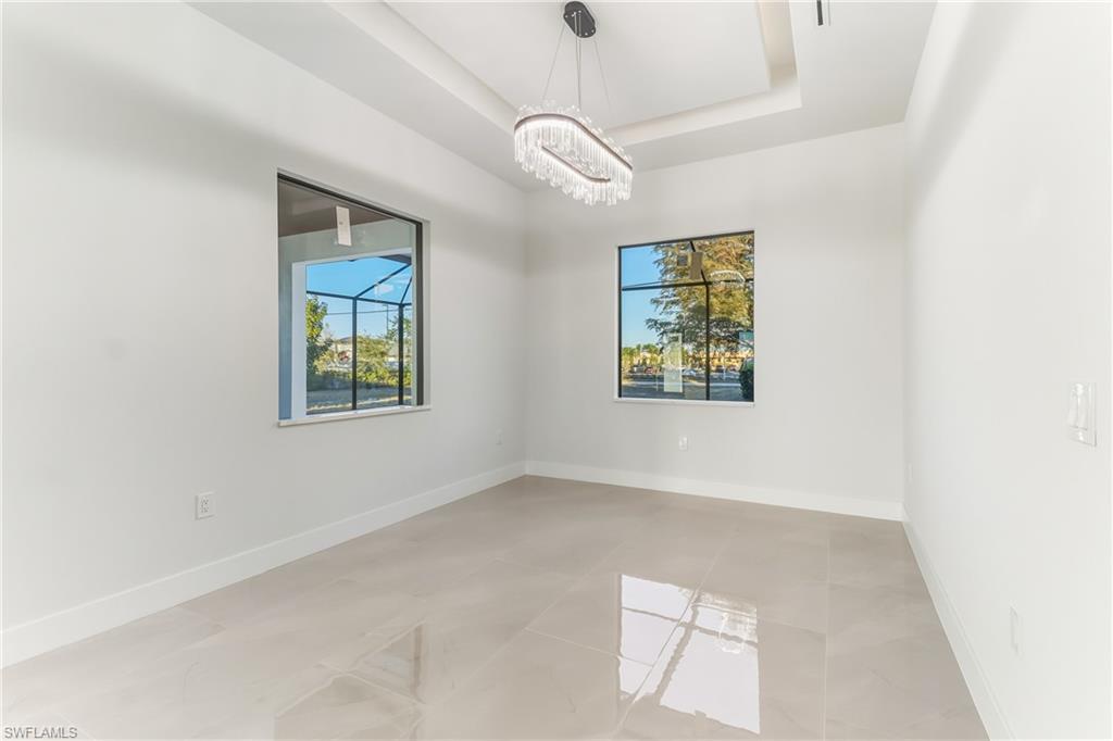 dining area with a tray ceiling, hanging lights, and light tile patterned flooring