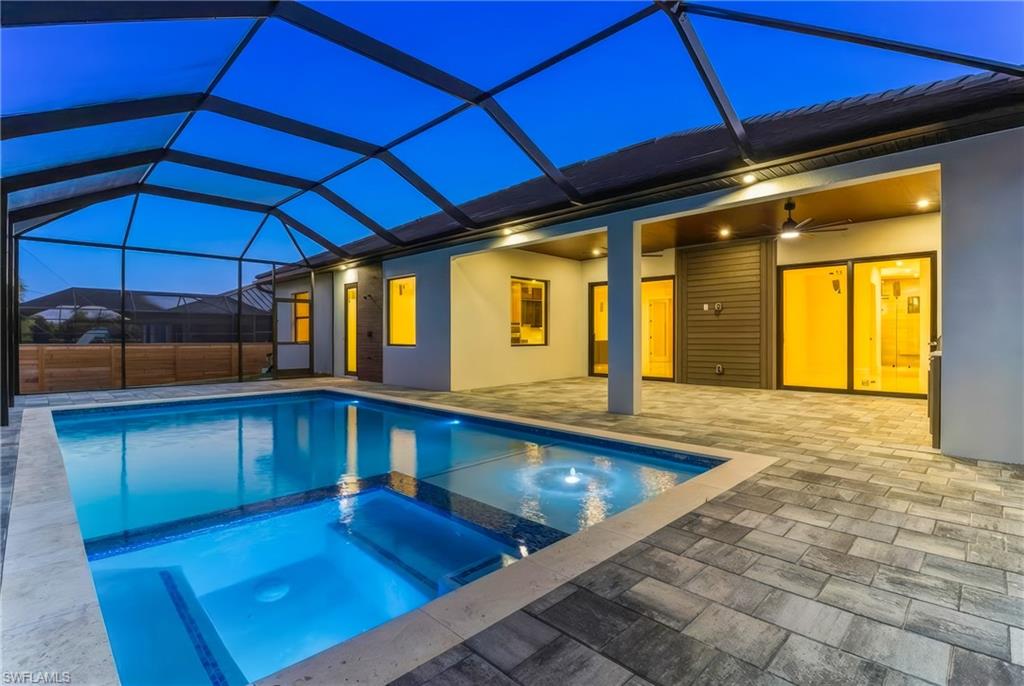 Relaxing pool / spa featuring screened enclosure, and a patio area