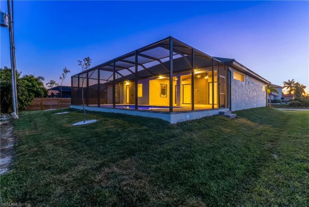 Back of property at dusk with glass enclosure and a sunroom