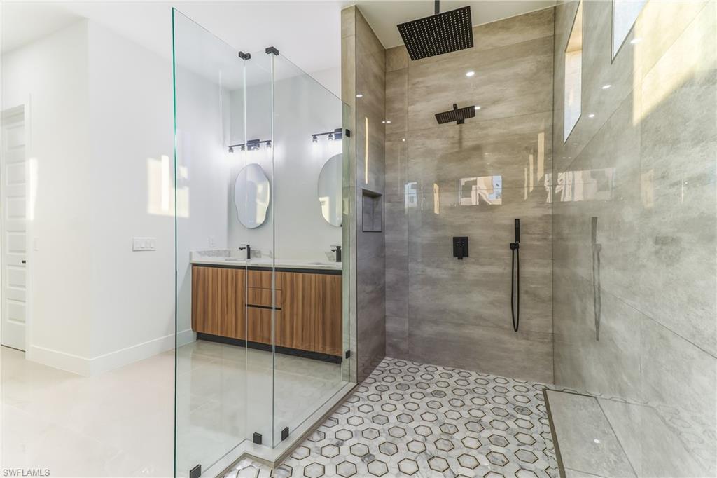 Bathroom with double vanity, a tile shower, and light tile patterned flooring