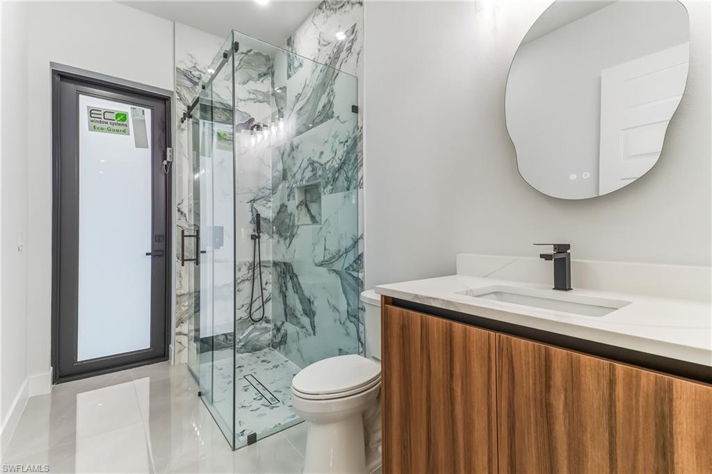 Bathroom featuring vanity and a marble finish shower