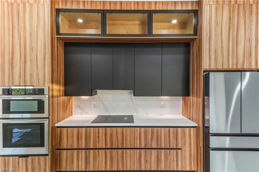 Kitchen with dual tone cabinets, modern cabinets, glass insert cabinets, stainless steel appliances, and backsplash
