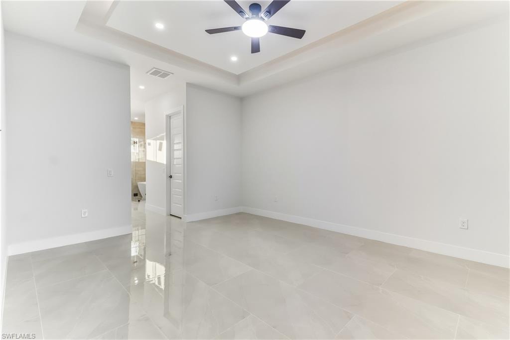 Primary bedroom with a raised ceiling, recessed lighting, and ceiling fan