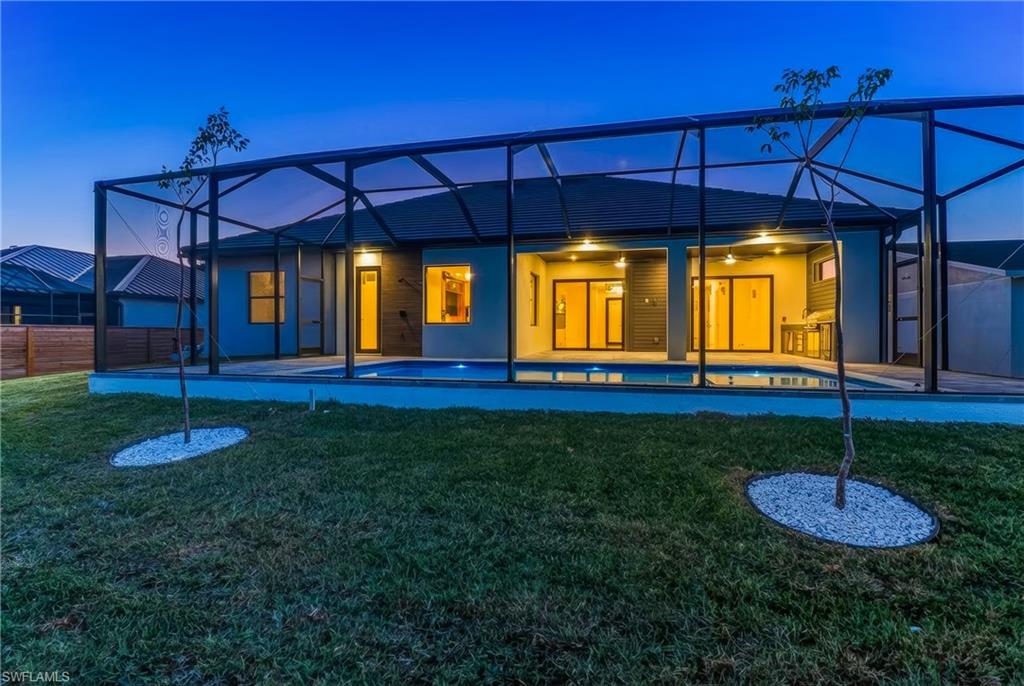 Back of home featuring screened enclosure for pool and spa and outdoor kitchen
