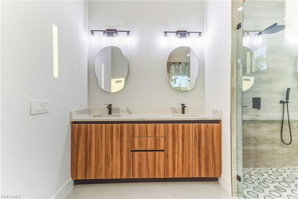 Bathroom featuring a stall shower, double vanity, and light tile patterned flooring