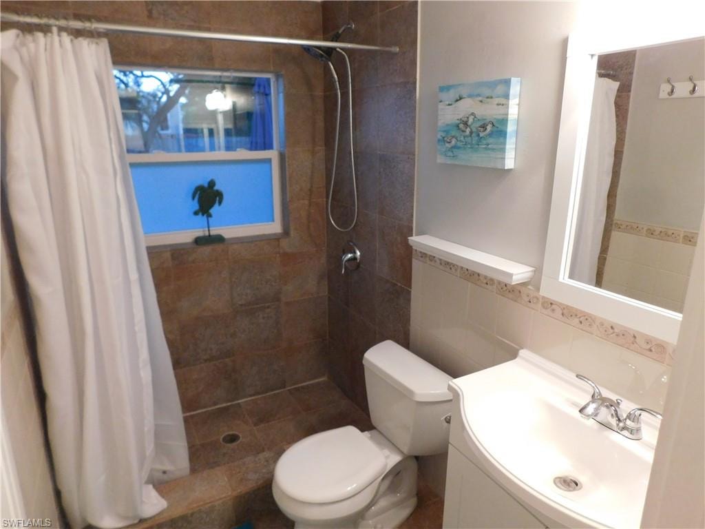 Bathroom with a stall shower, vanity, and tile walls