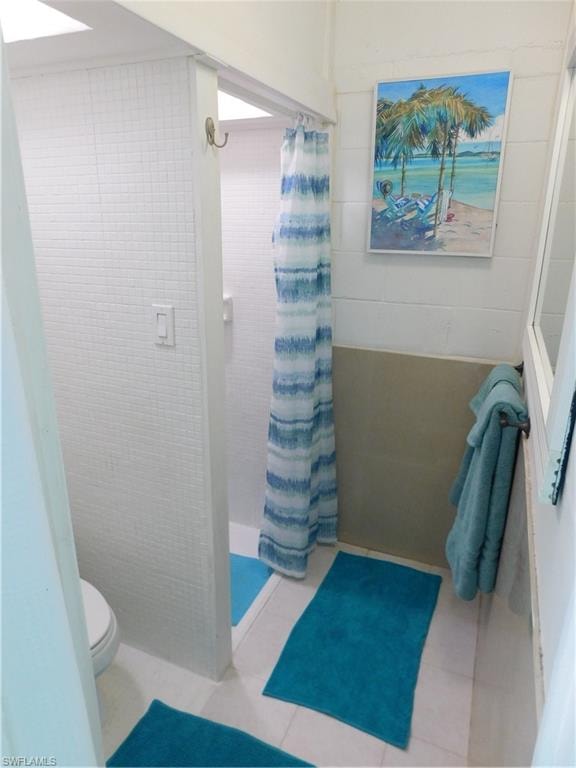 Bathroom featuring a shower stall and tile walls