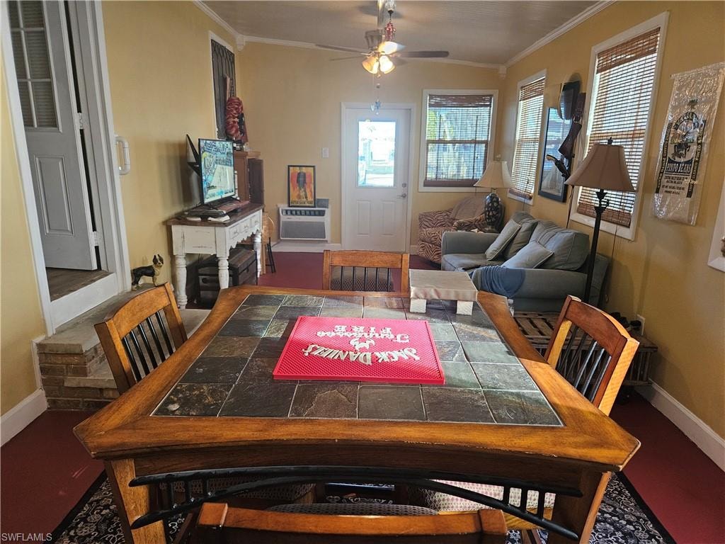Dining room featuring a wall mounted AC, a ceiling fan, baseboards, and ornamental molding