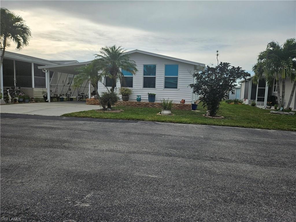 View of front of property featuring a front lawn and a carport
