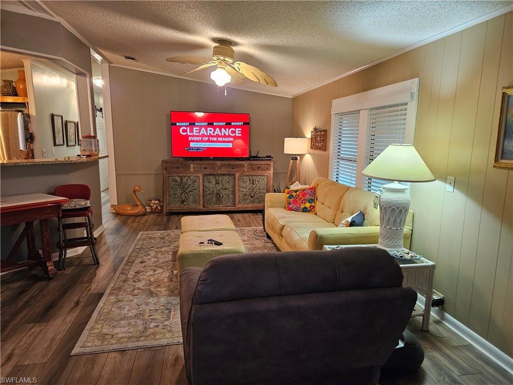Living room with hardwood / wood-style flooring, ceiling fan, crown molding, and a textured ceiling