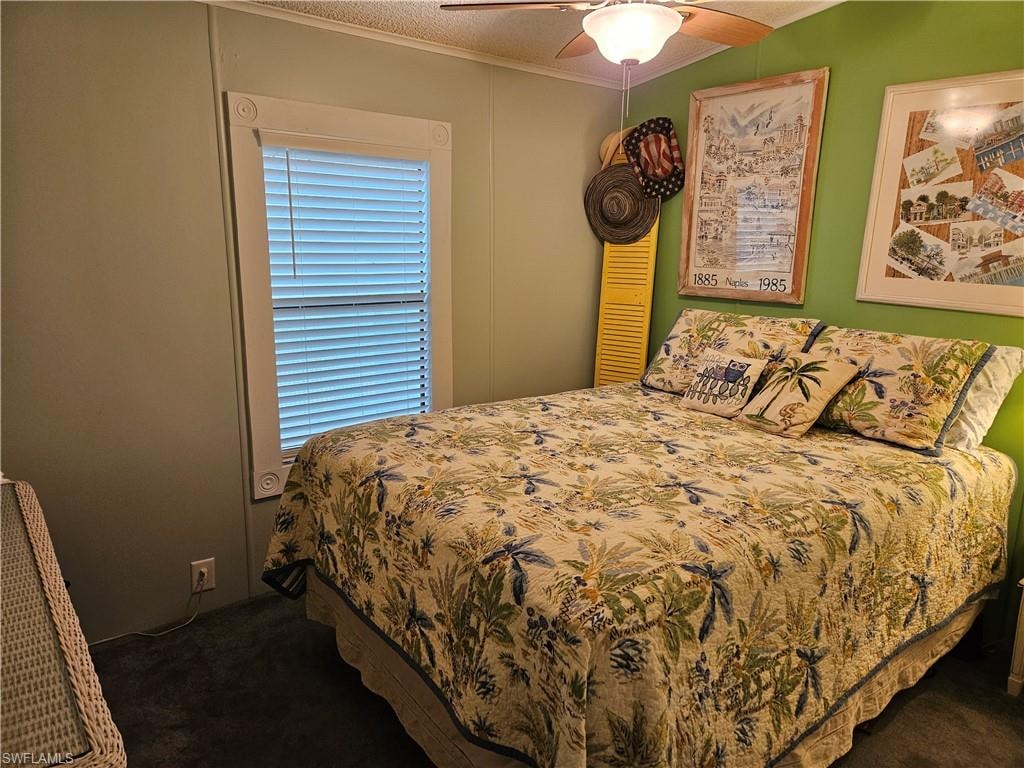 Bedroom with ceiling fan, ornamental molding, dark carpet, and a textured ceiling