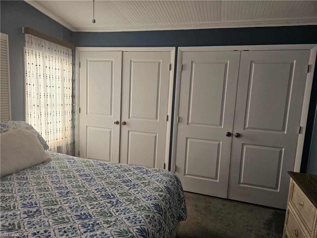Bedroom featuring two closets and dark colored carpet