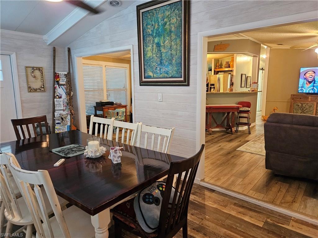 Dining area with ornamental molding, lofted ceiling, hardwood / wood-style floors, and ceiling fan