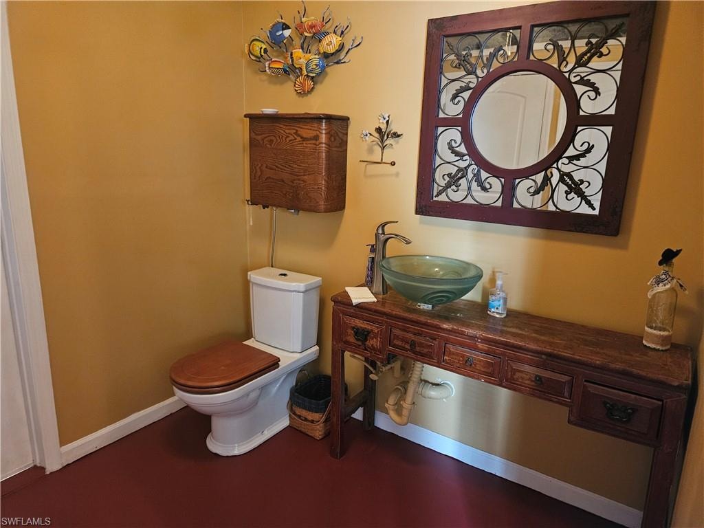 Half bathroom with a sink, baseboards, and toilet
