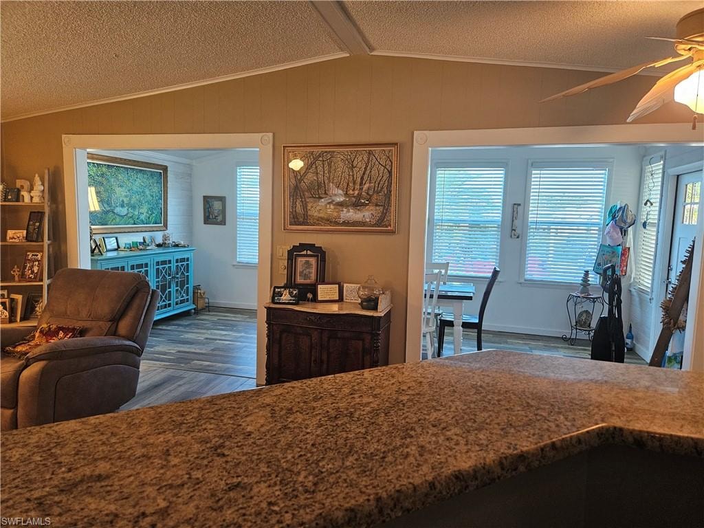 Kitchen featuring wood finished floors, a textured ceiling, ceiling fan, and vaulted ceiling