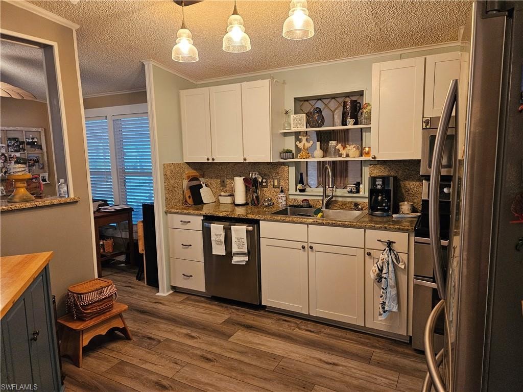 Kitchen featuring sink, white cabinetry, stainless steel appliances, dark hardwood / wood-style floors, and decorative light fixtures