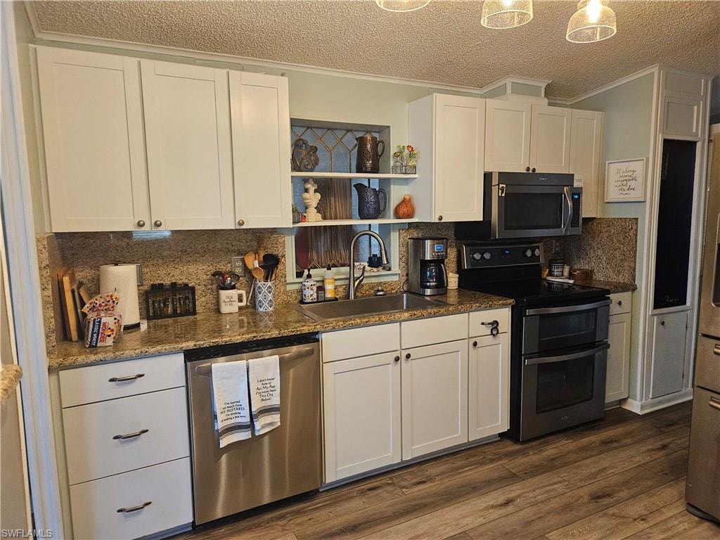 Kitchen featuring a sink, white cabinets, dark wood finished floors, and stainless steel appliances