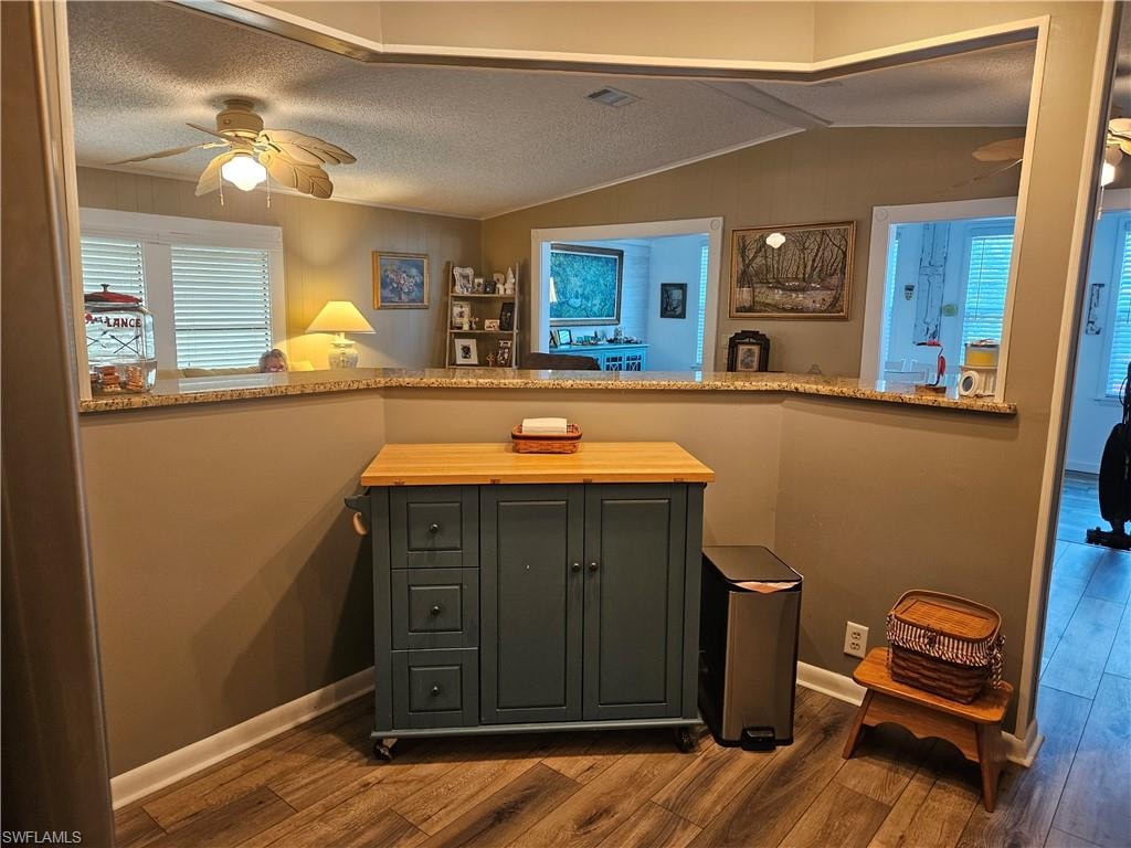 Bar with visible vents, a ceiling fan, a textured ceiling, dark wood finished floors, and lofted ceiling