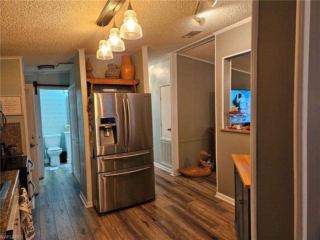 Kitchen with stainless steel refrigerator with ice dispenser, ornamental molding, dark hardwood / wood-style flooring, and hanging light fixtures