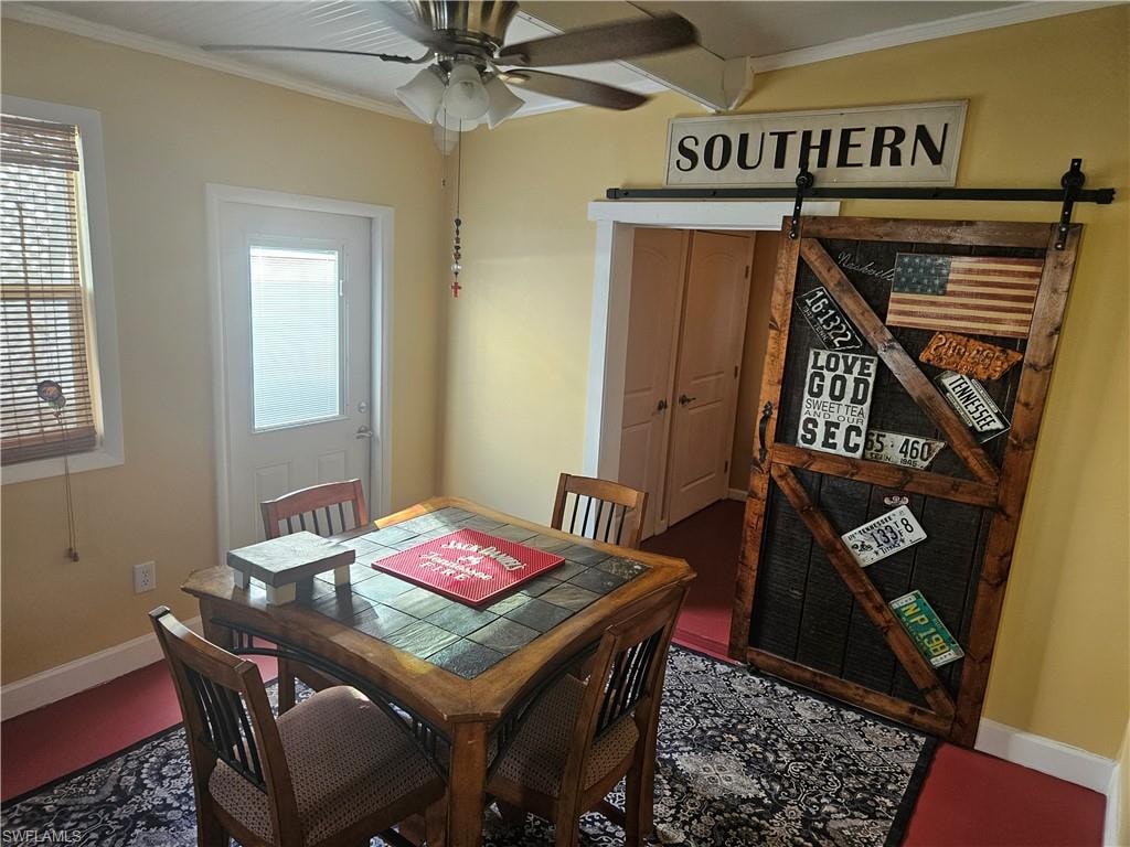 Dining area with a barn door, baseboards, ceiling fan, and crown molding